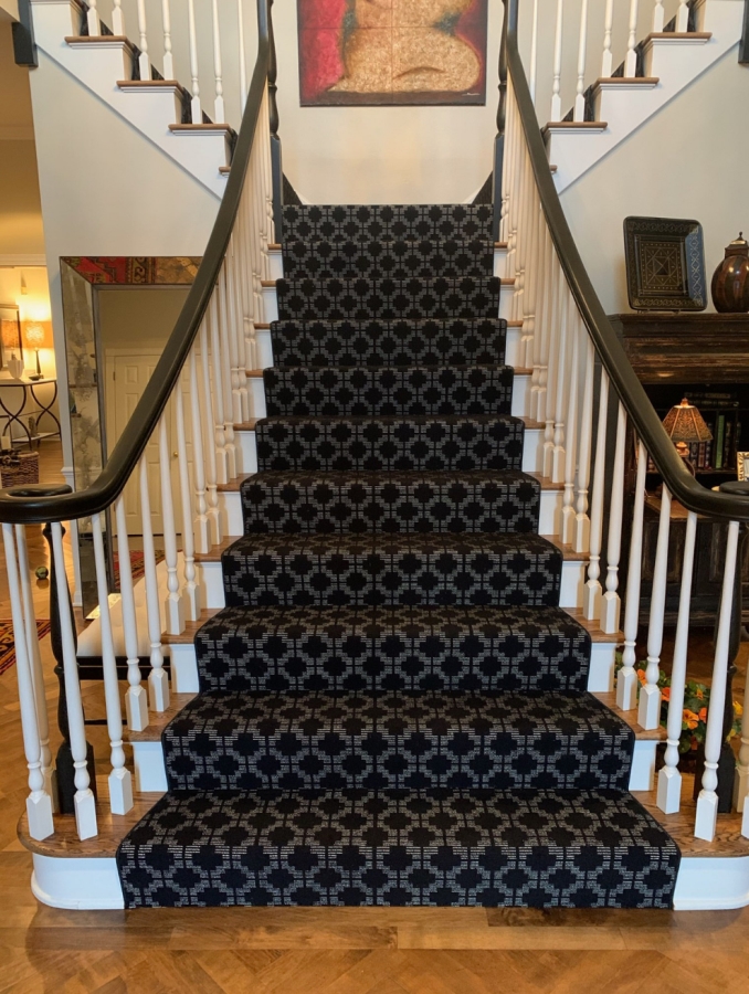 Split stairway with black patterned carpet. 